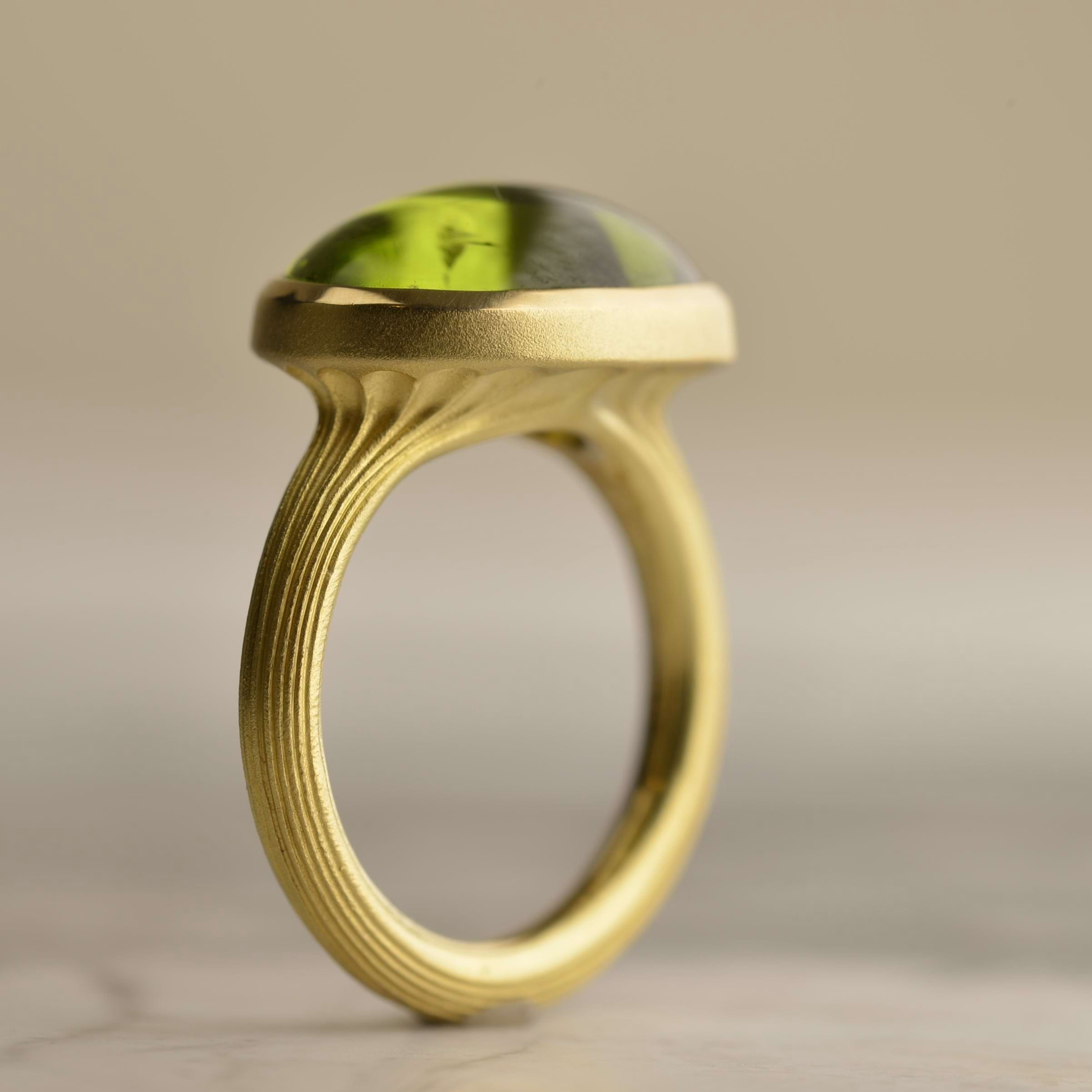 Side view of 18ct yellow gold ring with a 9.5ct vivid green cabochon peridot and fluted band detail. Handmade by Sydney jeweller Nicky Burles.