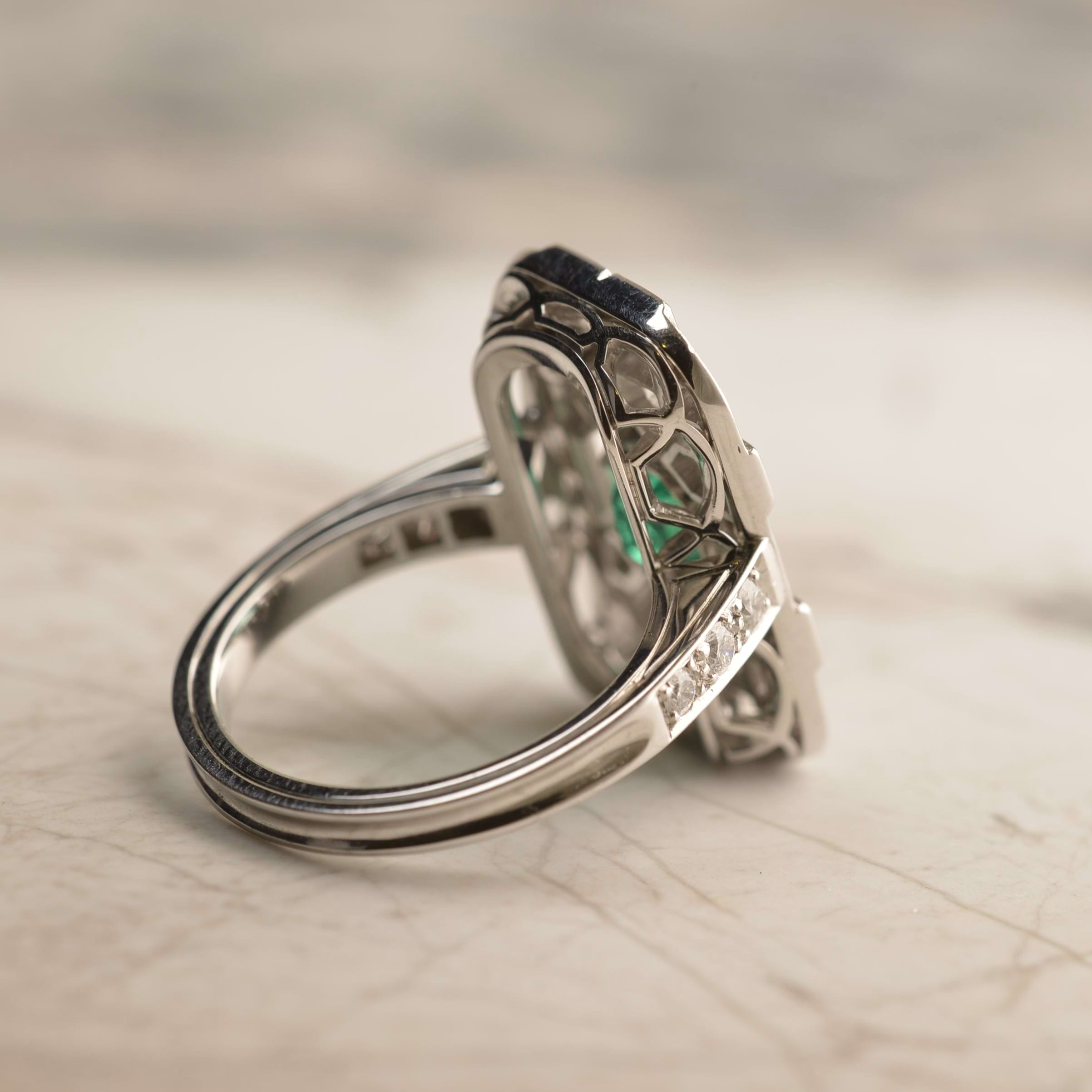 Back view of bespoke Colombian emerald tablet ring with ribbon like hand pierced basket and diamonds in the shoulder. Handmade in 18ct white gold by Sydney jeweller Nicky Burles.