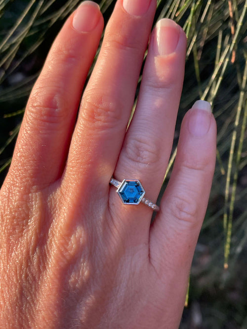 Wearing platinum ring featuring a hexagon-cut unheated teal sapphire from Madagascar, and 8 small diamonds in the shoulder. Handmade by Sydney jeweller Nicky Burles.