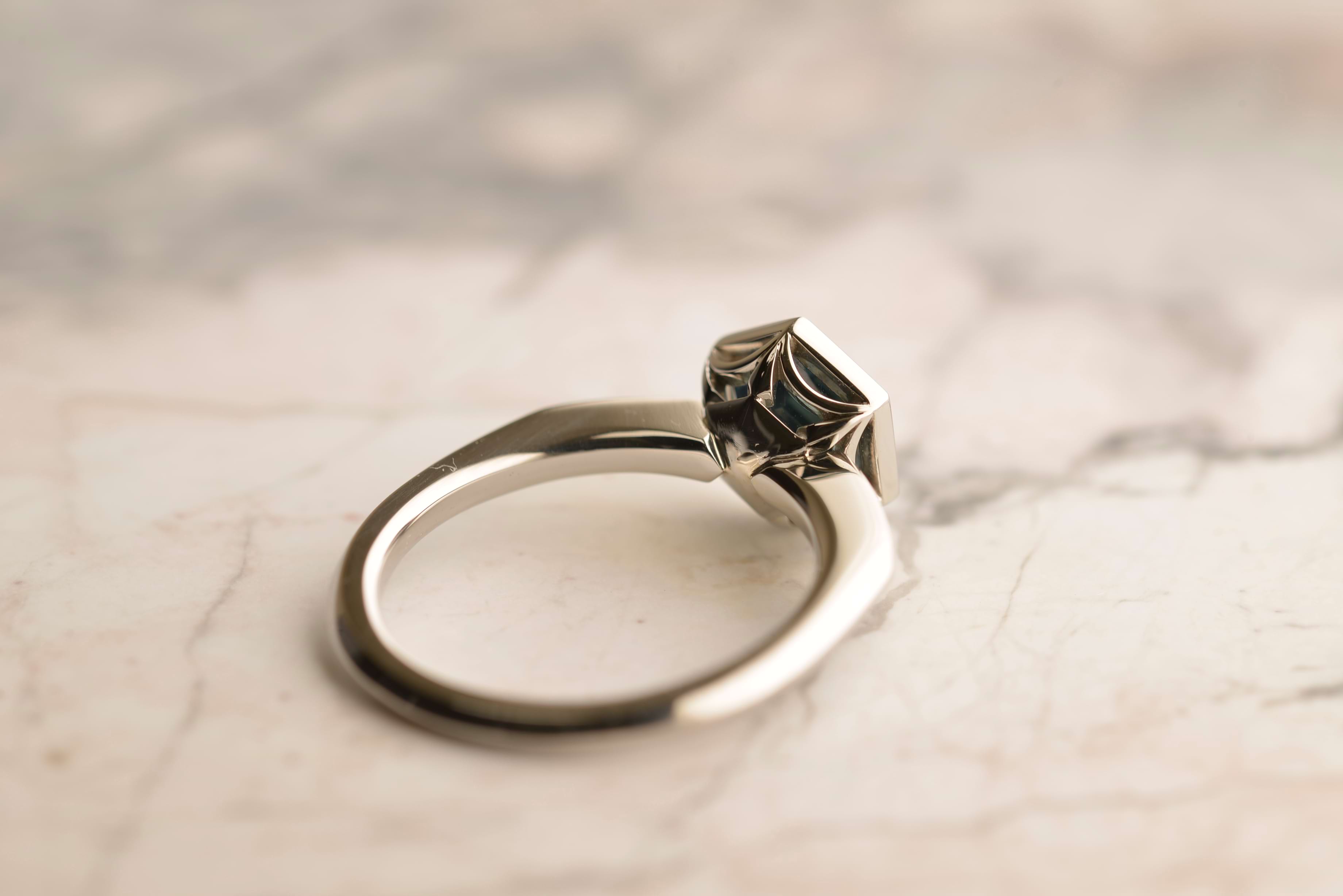Back view of platinum ring featuring a hexagon-cut unheated teal sapphire from Madagascar, and 8 small diamonds in the shoulder. Handmade by Sydney jeweller Nicky Burles.