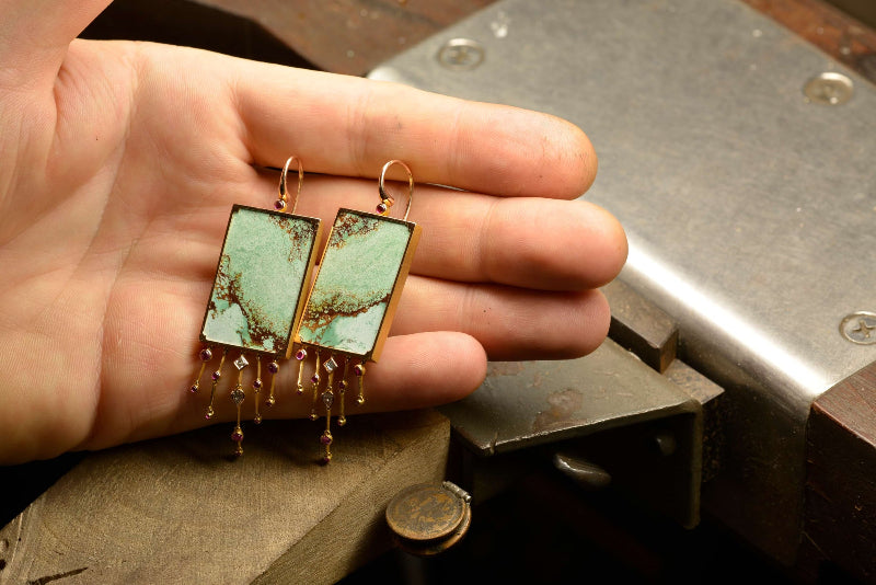Holding rose gold earrings featuring Australian turquoise tablets complemented by ruby cabochons and diamonds tassels. Handmade by Sydney jeweller Nicky Burles.
