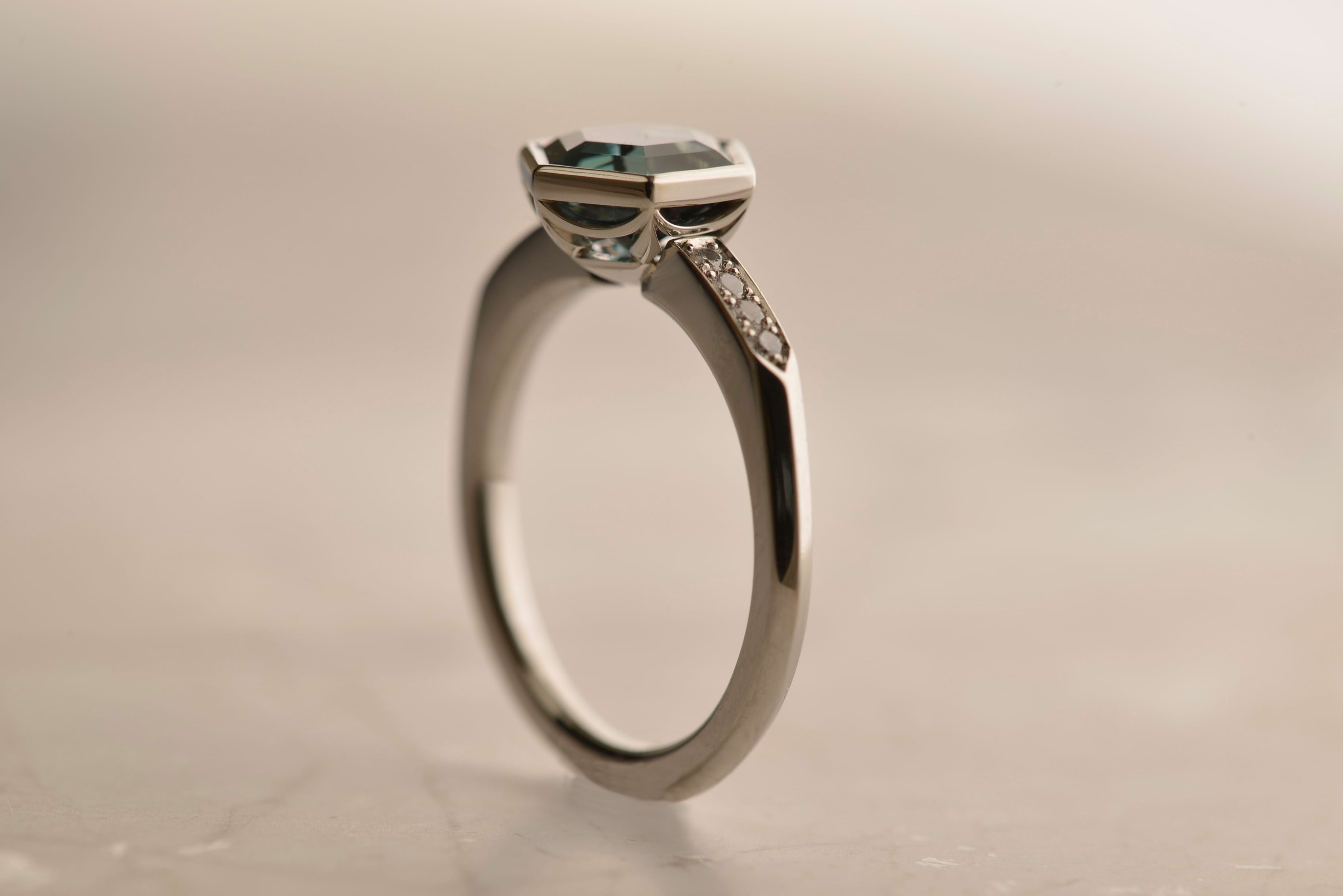 Side view of platinum ring featuring a hexagon-cut unheated teal sapphire from Madagascar, and 8 small diamonds in the shoulder. Handmade by Sydney jeweller Nicky Burles.
