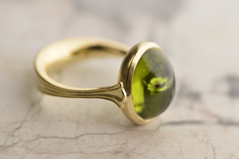  This signature Nicky Burles fluted Lotus ring features a 10-carat peridot set in 18-carat yellow gold.