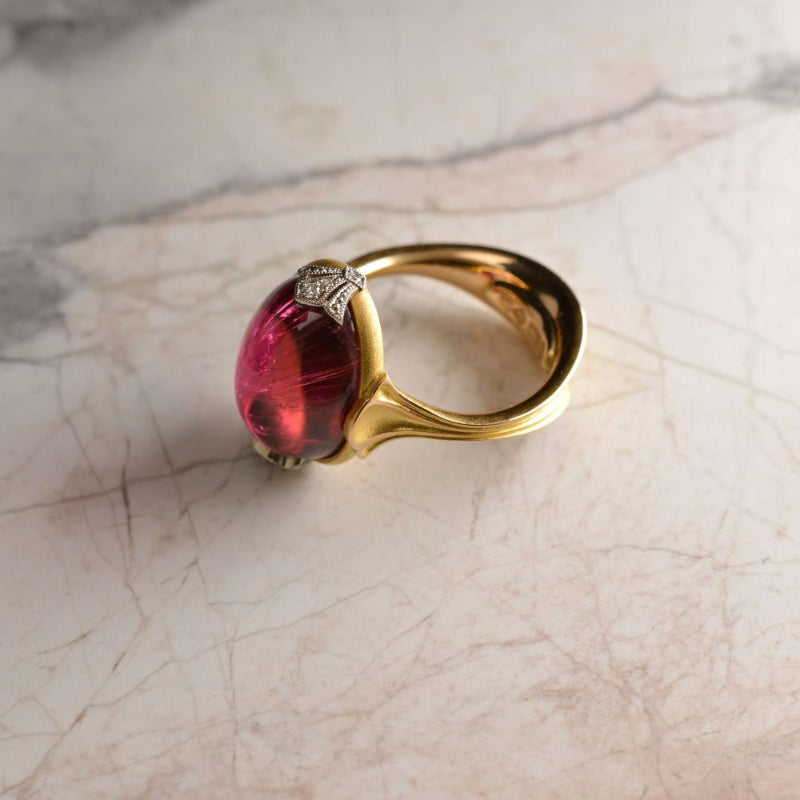 Bespoke 18ct rose gold dress ring with a 16ct raspberry rubellite tourmaline cabochon and diamond fleur-de-lis accents set in milgrain details in platinum. Handmade by Sydney jeweller Nicky Burles.